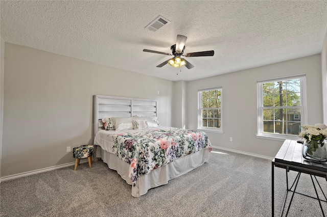 carpeted bedroom featuring baseboards, a textured ceiling, visible vents, and a ceiling fan