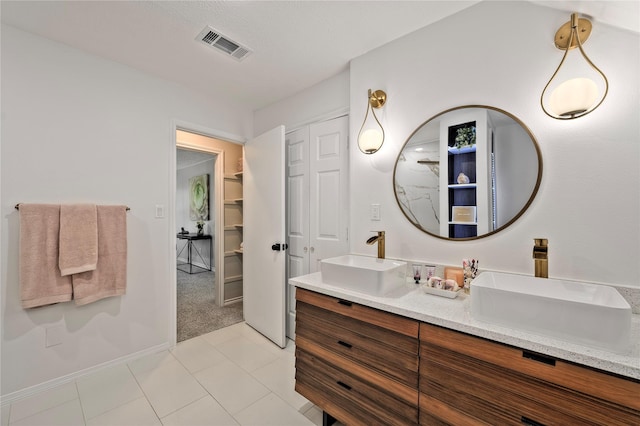 bathroom with double vanity, a sink, visible vents, and tile patterned floors