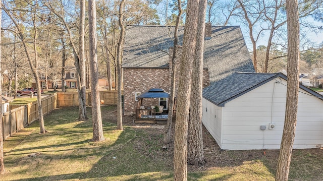 exterior space with a shingled roof, a fenced backyard, a lawn, and a wooden deck