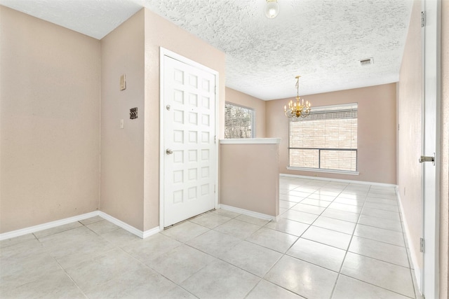 entryway with light tile patterned floors, baseboards, visible vents, a textured ceiling, and a chandelier