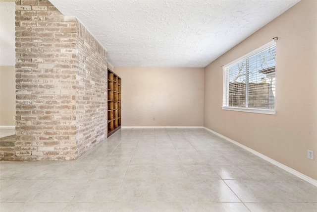 tiled empty room with baseboards and a textured ceiling