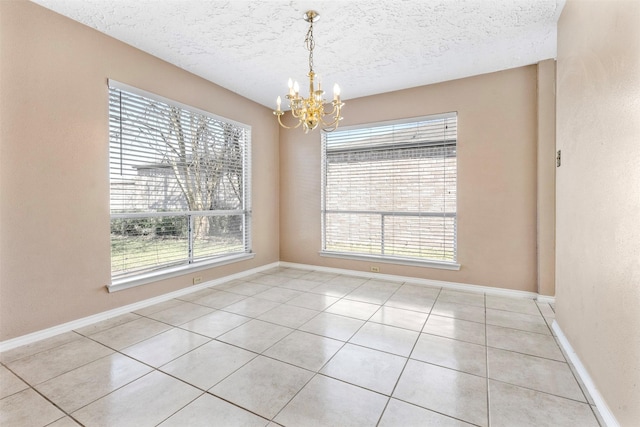 tiled spare room featuring baseboards, a chandelier, and a textured ceiling