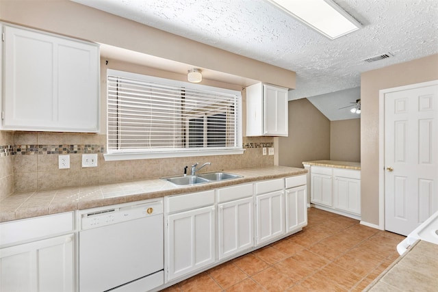 kitchen with white dishwasher, a sink, visible vents, white cabinetry, and decorative backsplash