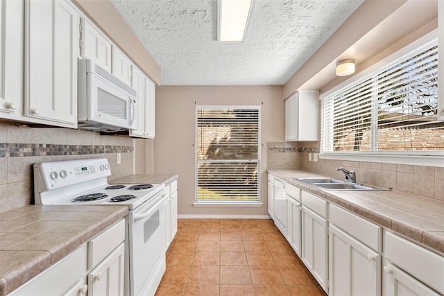 kitchen with white appliances, a sink, tile countertops, and light tile patterned floors