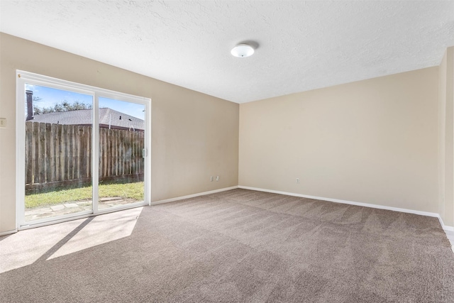 spare room with a textured ceiling, carpet, and baseboards