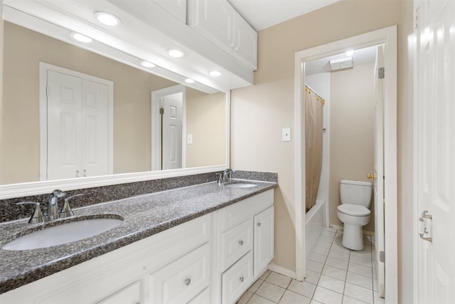 full bathroom with double vanity, tile patterned flooring, toilet, and a sink