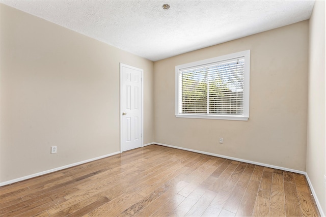 spare room featuring a textured ceiling, wood-type flooring, and baseboards