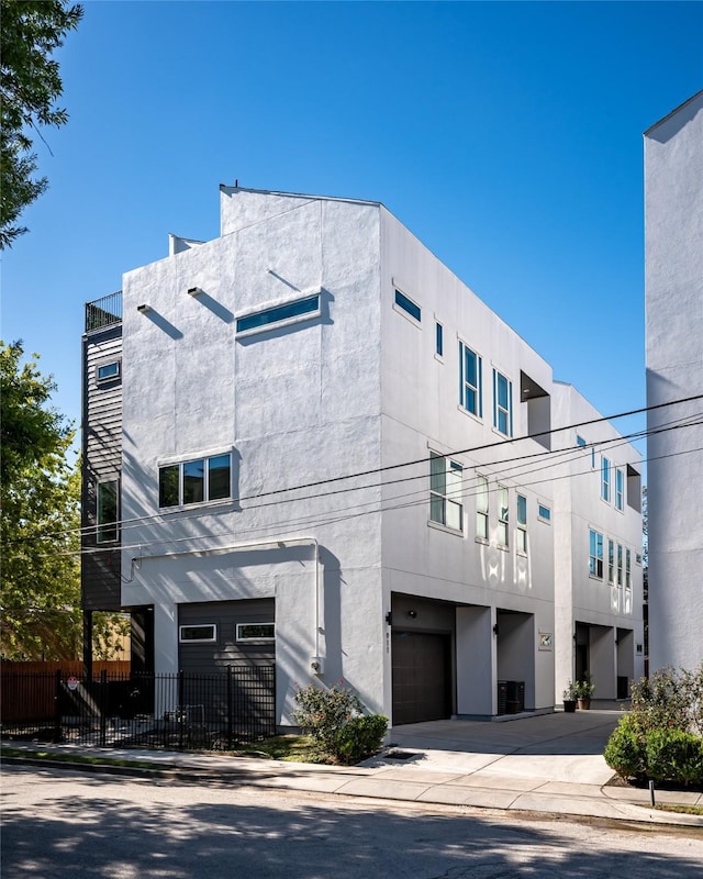 exterior space featuring a garage, fence, concrete driveway, and stucco siding