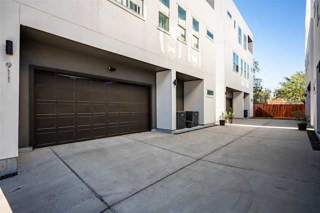 exterior space featuring concrete driveway, cooling unit, and fence