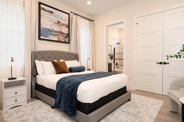 bedroom with ensuite bath, light wood-style flooring, a closet, and recessed lighting