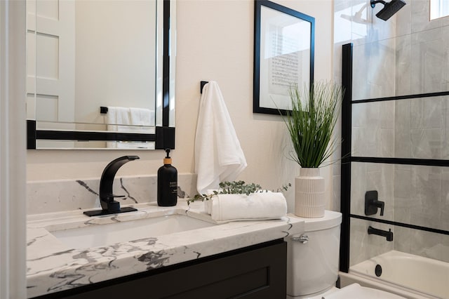 full bathroom with combined bath / shower with glass door, vanity, and toilet