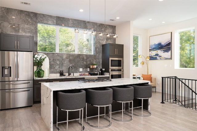 kitchen with light stone countertops, backsplash, stainless steel appliances, and a sink