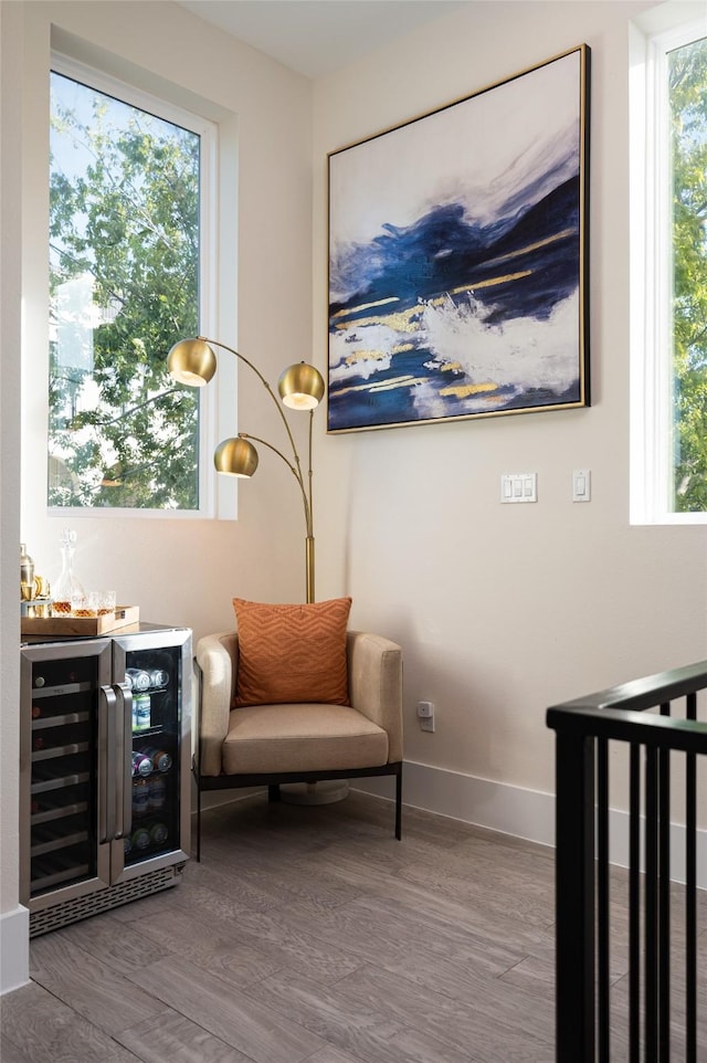 sitting room with beverage cooler, a bar, and a healthy amount of sunlight