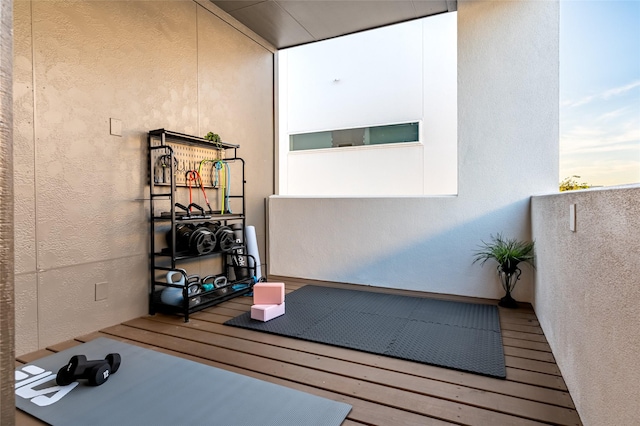 workout area featuring wood finished floors and a textured wall