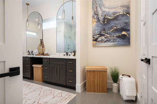 full bath with double vanity, baseboards, tile patterned floors, a shower stall, and a sink