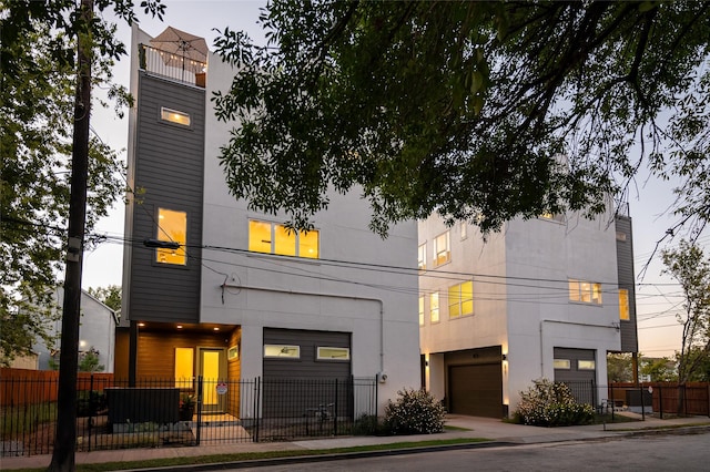 contemporary house with a garage, fence, and stucco siding