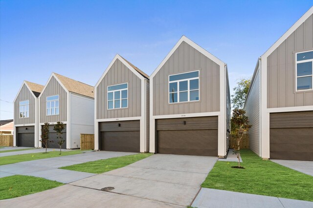 1016 Patton St, Houston, TX 77009 - view of front facade with board and batten siding, concrete driveway, a front lawn, and a garage