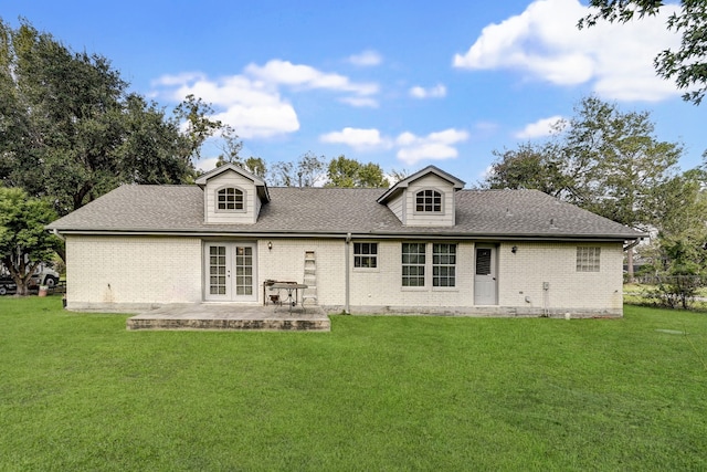 rear view of house featuring brick siding, a shingled roof, a yard, french doors, and a patio area