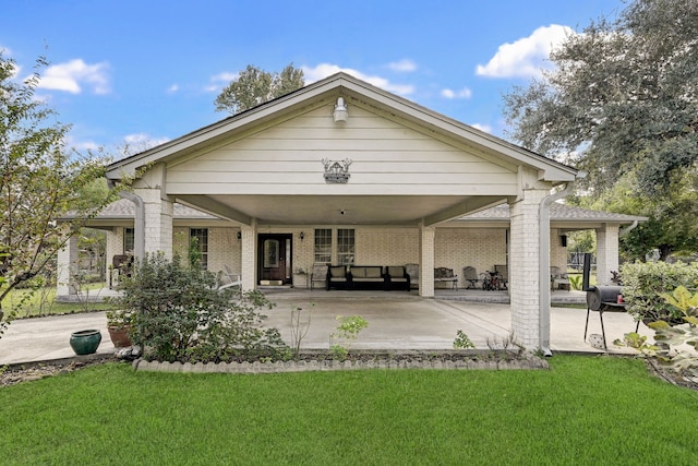 back of house with brick siding, a lawn, and a patio area