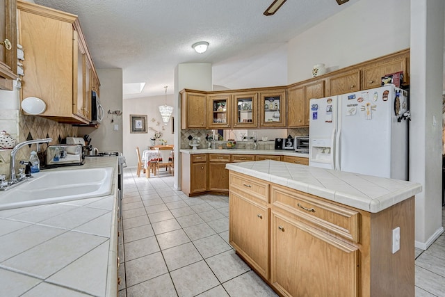 kitchen featuring decorative backsplash, gas range, white fridge with ice dispenser, a sink, and light tile patterned flooring