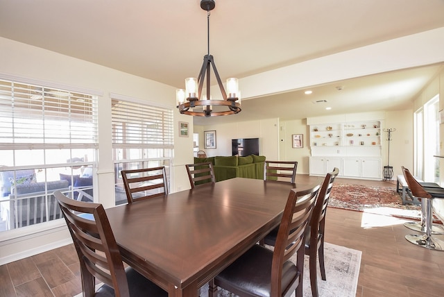 dining space featuring plenty of natural light, wood finished floors, and a notable chandelier