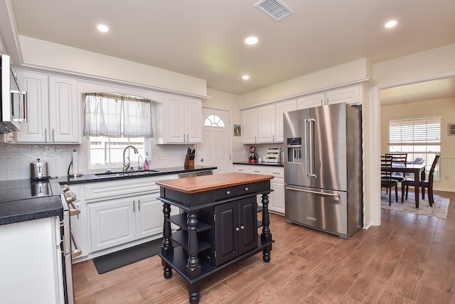 kitchen featuring a center island, stainless steel appliances, visible vents, white cabinetry, and a sink