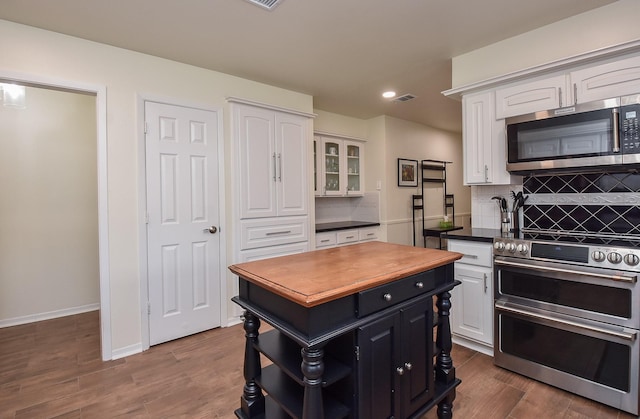 kitchen with a center island, open shelves, decorative backsplash, appliances with stainless steel finishes, and white cabinets