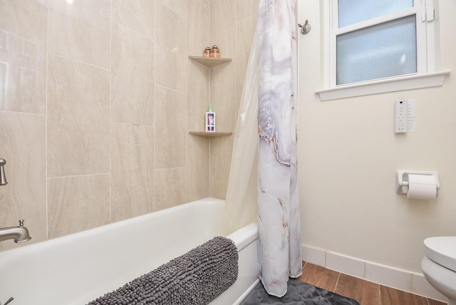 full bath featuring baseboards, shower / bathtub combination with curtain, toilet, and wood finished floors