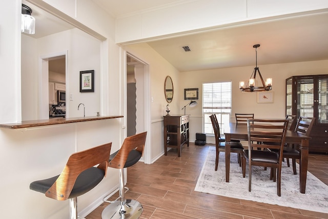 dining area with baseboards, wood tiled floor, visible vents, and a notable chandelier