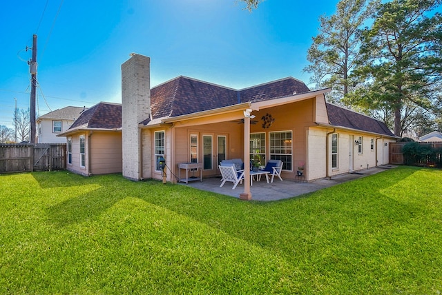 rear view of house with french doors, a fenced backyard, a chimney, and roof with shingles