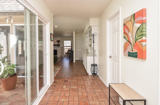 hallway with brick floor and baseboards