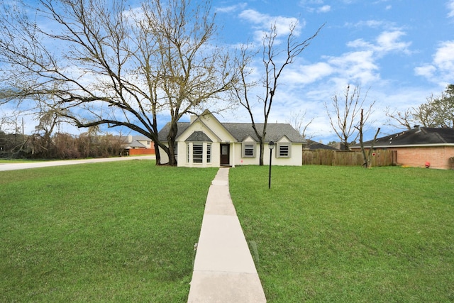 view of front of house featuring a shingled roof, fence, and a front yard