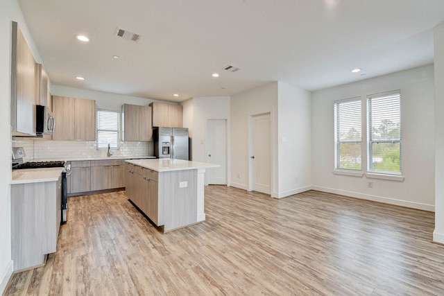 kitchen featuring a kitchen island, light wood-style floors, light countertops, appliances with stainless steel finishes, and modern cabinets