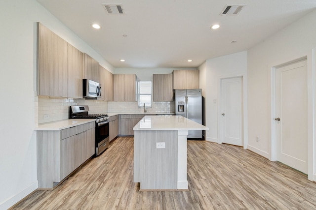 kitchen with appliances with stainless steel finishes, modern cabinets, visible vents, and a center island