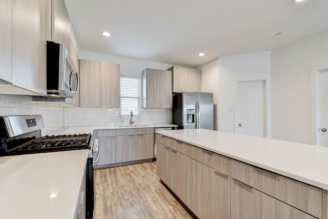 kitchen with a sink, light countertops, appliances with stainless steel finishes, backsplash, and light brown cabinetry