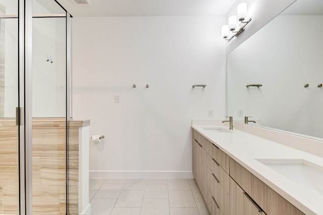 bathroom with double vanity, a shower with shower door, a sink, baseboards, and tile patterned floors