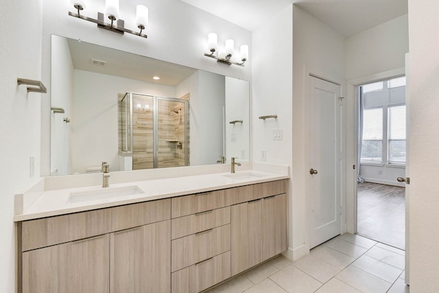 bathroom featuring double vanity, tile patterned floors, a sink, and a shower stall