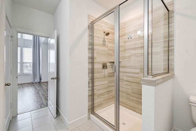 bathroom featuring tile patterned flooring, baseboards, a shower stall, and toilet