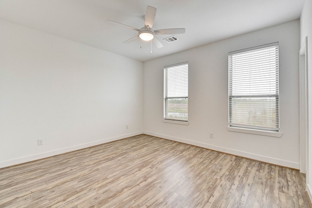 spare room with baseboards, ceiling fan, visible vents, and light wood-style floors