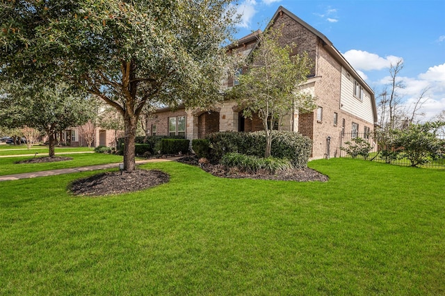 view of front of house with brick siding, a front yard, and fence