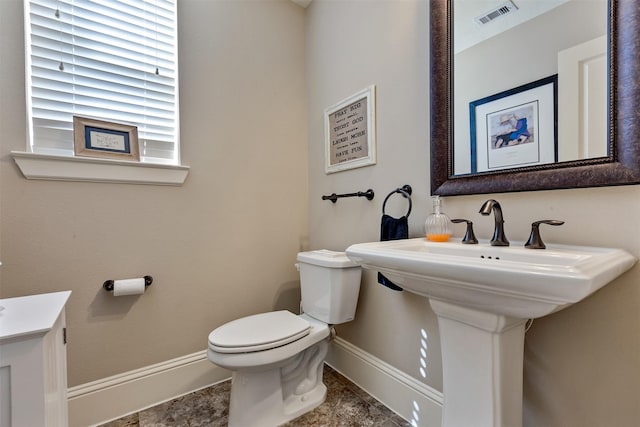 bathroom with toilet, baseboards, visible vents, and a sink