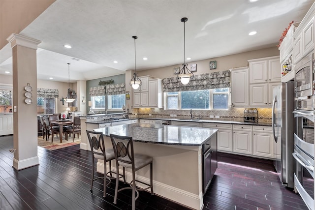 kitchen with backsplash, appliances with stainless steel finishes, dark wood finished floors, and a peninsula