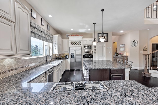 kitchen featuring arched walkways, a sink, stainless steel appliances, dark wood-type flooring, and backsplash