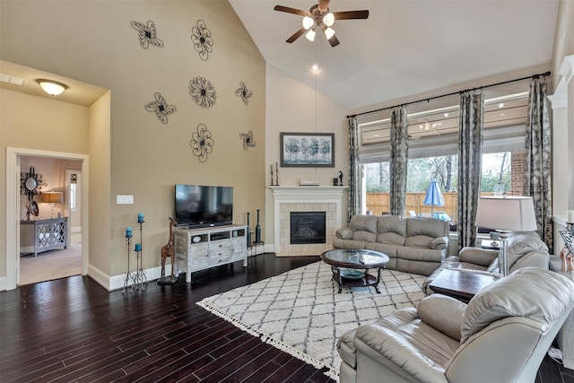 living room featuring a ceiling fan, baseboards, wood finished floors, high vaulted ceiling, and a tile fireplace