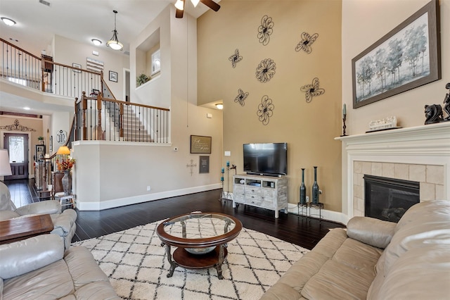 living room with a tiled fireplace, stairway, wood finished floors, and baseboards