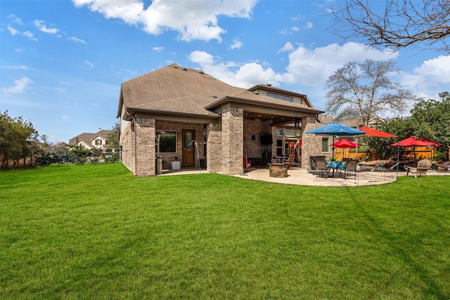 back of property featuring brick siding, a shingled roof, fence, a lawn, and a patio area