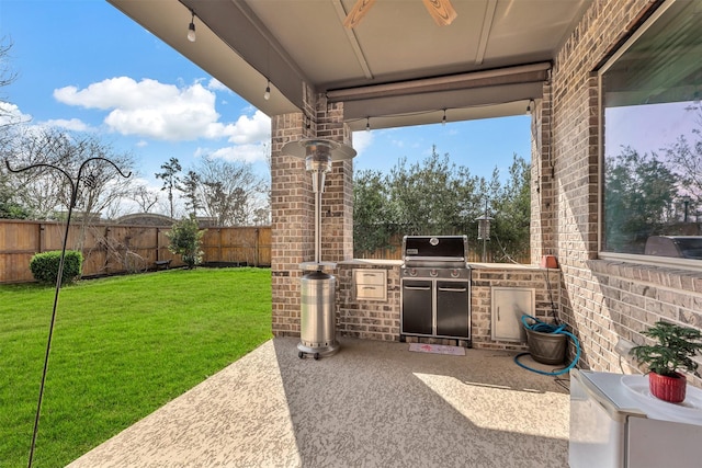 view of patio with grilling area, a fenced backyard, and an outdoor kitchen