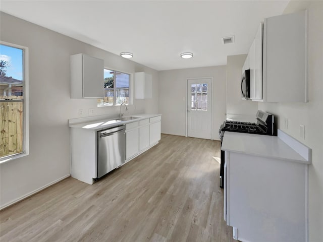 kitchen featuring light wood finished floors, visible vents, white cabinets, stainless steel appliances, and light countertops