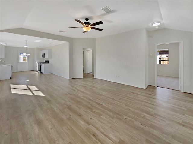 unfurnished living room featuring vaulted ceiling, light wood-style flooring, visible vents, and a ceiling fan