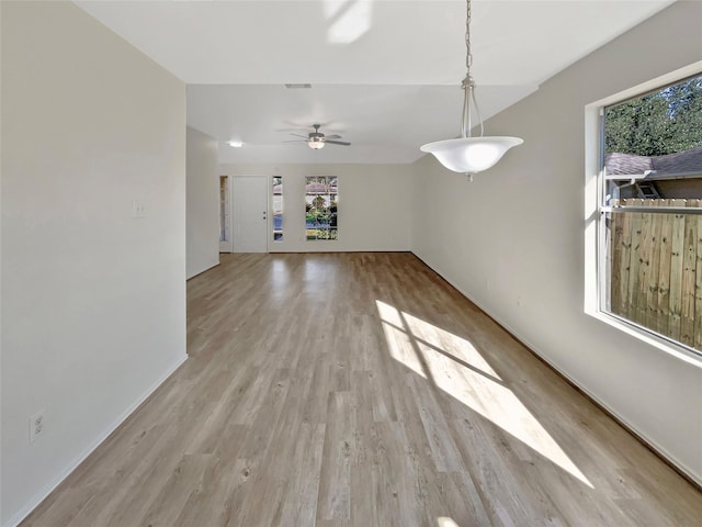 unfurnished living room featuring baseboards, visible vents, ceiling fan, and light wood finished floors